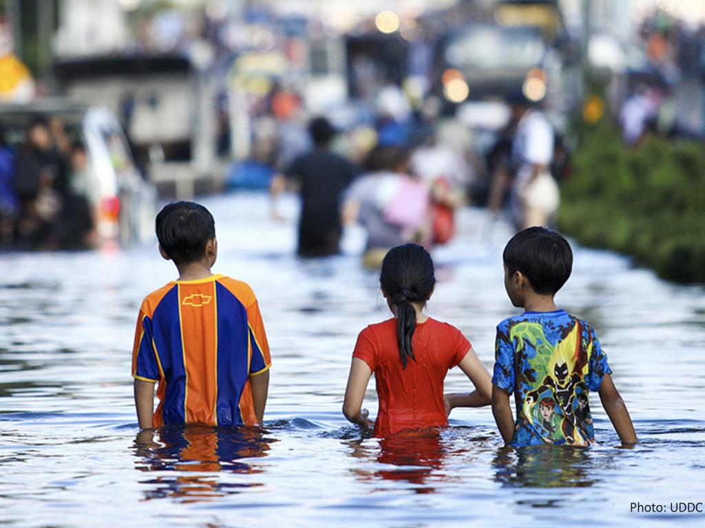 Three children cross a flooded street